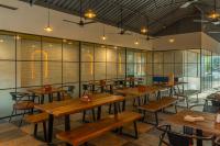 Un restaurante con mesas y sillas de madera y ventanas. en The Hosteller Goa, Candolim, en Candolim
