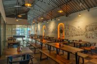 un restaurante con mesas de madera y un mural en la pared en The Hosteller Goa, Candolim, en Candolim