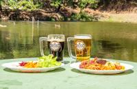 a table with two plates of food and two glasses of beer at Parque Pousada Macaquinho Turismo in Serra Negra
