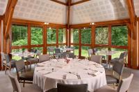 a dining room with tables and chairs and windows at Hôtel Centre Port-Royal in Saint-Lambert