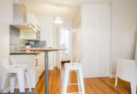 a kitchen with a table and two white stools at Les Loges des Chalets in Toulouse