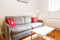 a living room with a couch with two red pillows at Les Loges des Chalets in Toulouse