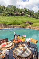 a table with plates of food and drinks and a pool at Pu Luong EcoLuxe Resort & Spa in Pu Luong