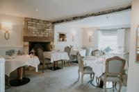 a dining room with white tables and chairs and a fireplace at Number Four at Stow in Stow on the Wold