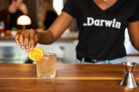 Uma mulher está espremendo uma laranja em uma bebida. em voco The Darwin - Atlanta Midtown by IHG em Atlanta
