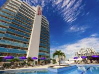 un hotel con piscina, sillas y sombrillas púrpuras en Mercure Rio de Janeiro Nova Iguaçu, en Nova Iguaçu