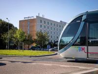 un autobús conduciendo por una calle frente a un edificio en Mercure Bordeaux Aéroport, en Mérignac