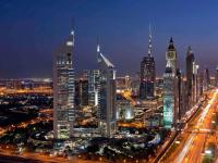 un perfil urbano por la noche con una torre de reloj en Swissôtel Al Murooj Dubai, en Dubái
