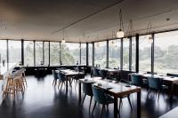 Un restaurante con mesas y sillas y grandes ventanales. en Bom Sucesso Resort, en Vau