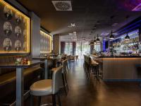 un restaurante con barra con sillas y mesas en Pullman Munich, en Múnich
