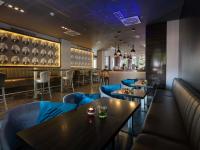 Un restaurante con mesas y sillas y un bar. en Pullman Munich, en Múnich