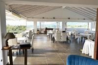a restaurant with white tables and chairs and a piano at Likithos Village in Agios Georgios