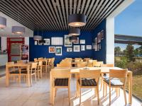 a restaurant with wooden tables and chairs and a blue wall at Greet hotel Darmstadt - an Accor hotel - in Darmstadt