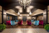アイオワシティにあるThe Highlander Hotel, Ascend Hotel Collectionのテーブルと椅子、シャンデリアが備わる広い客室です。