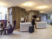 Un hombre de pie en un mostrador en un vestíbulo. en Novotel Coventry, en Coventry
