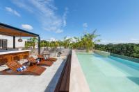 una piscina con tumbonas y sillas junto a una casa en Irie Tulum, en Tulum