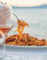 una persona che mangia spaghetti su un piatto con una forchetta di Victoria's Suites Corfu a Lefkimmi