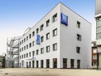 a white building with blue signs on the side of it at ibis budget Aachen City in Aachen