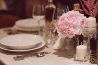 a table with plates and candles and pink flowers at C&C Residence Hotel in Bacău