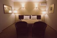 a bedroom with a bed with two chairs and a mirror at C&C Residence Hotel in Bacău