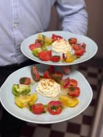 Dos platos de comida con tomates y verduras encima. en Logis Hotel Spa Restaurant Au Site Normand, en Clécy