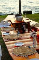 a wooden picnic table with plates and wine glasses at Bayside Resort Lake Victoria- Mbita in Mbita
