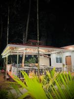 een huis met een witte veranda met verlichting erop bij Seaside Beach Resort in Diveagar