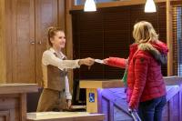a woman is handing another woman a wii remote at CGH Résidences &amp; Spas Chalet Les Marmottons in La Rosière