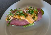 une plaque blanche avec un sandwich à la viande et aux légumes dans l'établissement Cozy Corner, à Bloemfontein