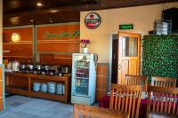 ein Restaurant mit einem Kühlschrank, einem Tisch und Stühlen in der Unterkunft Cemara Indah Hotel in Bromo