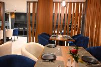 バンガロールにあるGood One Suitesのダイニングルーム(テーブル2台、青い椅子付)