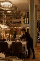 una mujer está poniendo una mesa en un restaurante en Nimb Hotel, en Copenhague