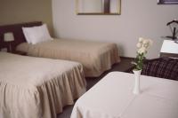a hotel room with two beds and a vase with flowers on a table at C&C Residence Hotel in Bacău