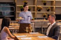 a waitress holding a plate of food in a restaurant at Mercure Darwin Airport Resort in Darwin