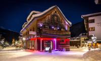 un edificio è illuminato di notte nella neve di Murrmel Apartments a Sankt Anton am Arlberg