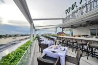 a restaurant with white tables and chairs on a balcony at Riva Arun Bangkok in Bangkok