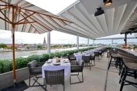 a restaurant with white tables and chairs and windows at Riva Arun Bangkok in Bangkok