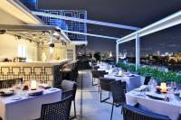 a restaurant with white tables and chairs and a view of the city at Riva Arun Bangkok in Bangkok
