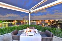 a dinner table on a balcony with a view of a river at Riva Arun Bangkok in Bangkok