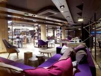 a room with a purple couch and tables and chairs at Campanile Nancy Centre - Gare in Nancy