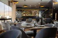 伊洛VIP Hotel的一家有桌椅和酒吧的餐厅