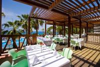 un ristorante con tavoli bianchi e sedie verdi e l'oceano di Fantasia Deluxe Hotel a Kusadası