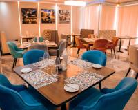 a restaurant with wooden tables and blue chairs at Swiss International Rancho Valeria, Warri in Warri