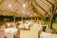 un restaurante con mesas y sillas blancas en la arena en Coin Sauvage, en Ambatozavavy