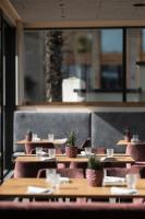 a row of tables in a restaurant with potted plants at Hotel Landgasthof Weingut Seeperle in Caldaro
