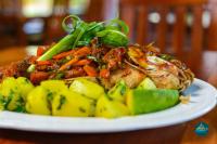 um prato de alimentos com carne e legumes sobre uma mesa em Nile Bridge Cottages em Jinja