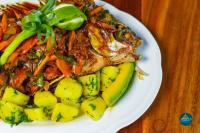 um prato de alimentos com carne e legumes sobre uma mesa em Nile Bridge Cottages em Jinja