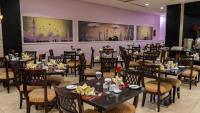 uma sala de jantar com mesas e cadeiras e paredes roxas em فندق الصفوة البرج الثالث Al Safwah Hotel Third Tower 3 em Meca