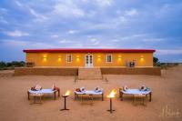 un groupe de chaises et de tables devant une maison dans l'établissement Helsinki Desert Camp, à Jaisalmer