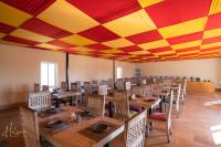 une salle à manger avec des tables et des chaises en bois et un plafond rouge et jaune dans l'établissement Helsinki Desert Camp, à Jaisalmer